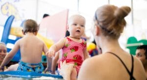 Mother with her child in the pool during bathtime babies swim class