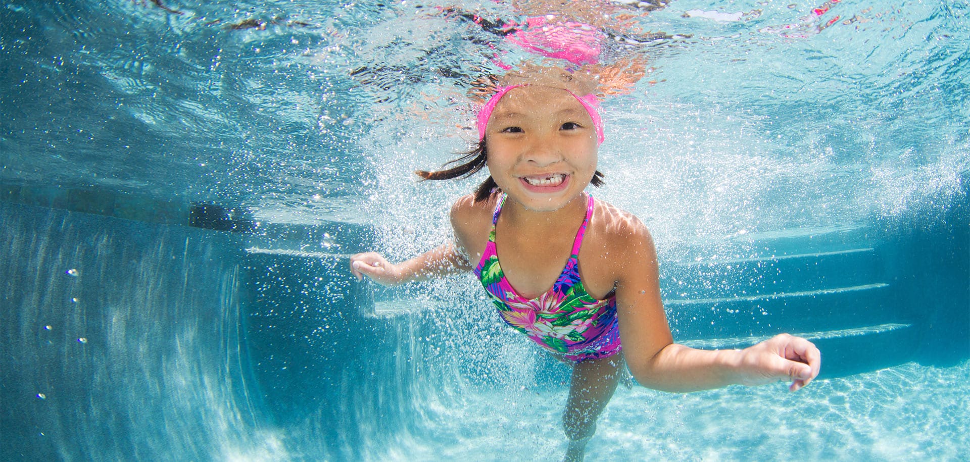 Smiling girl swimming underwater