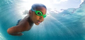 Boy with green goggles swimming underwater