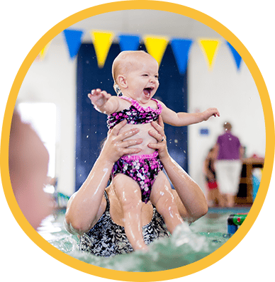 Baby laughing and kicking in the pool as a parent lifts them up