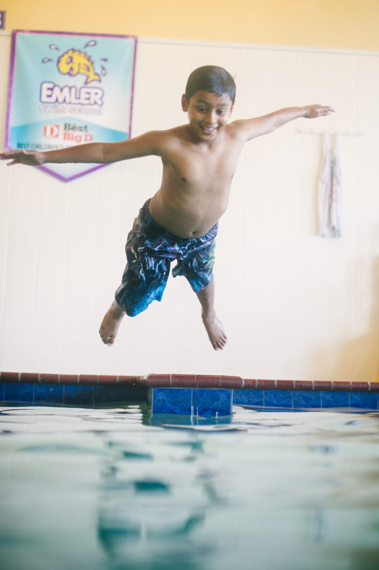 A boy jumps into the indoor pool at Emler's Frisco swim school location