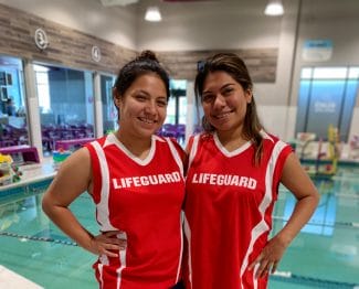 Two female lifeguards standing in front of an indoor pool
