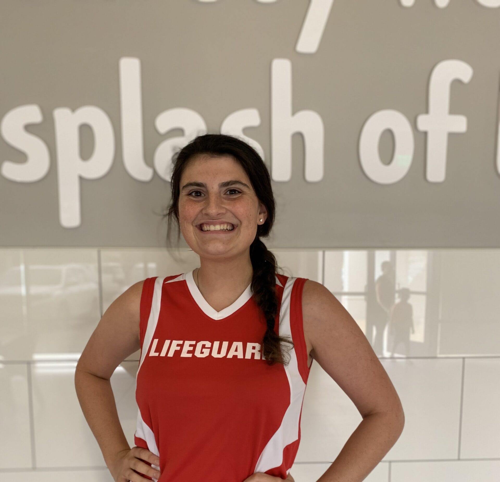 Smiling female Emler lifeguard in front of pool wall