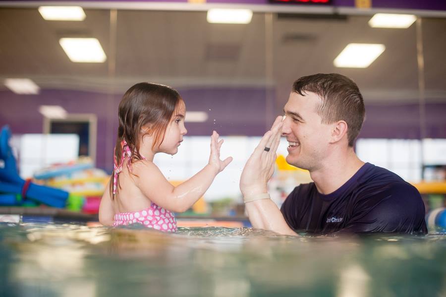 A father high fiving his daughter in the pool