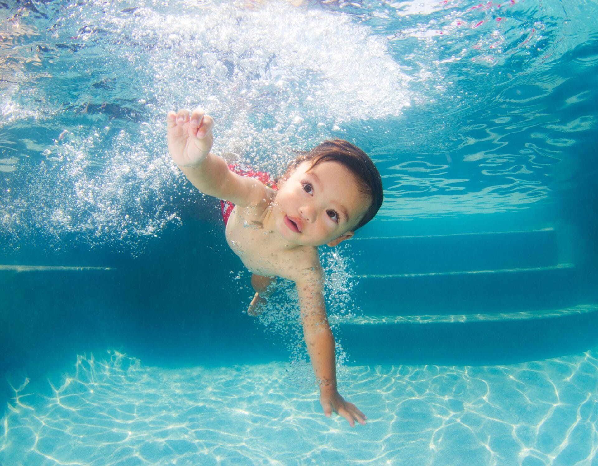 A boy reaching out as he swims underwater